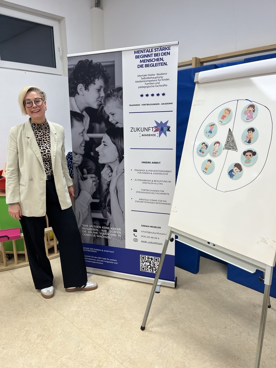 Sarah bei einer Fortbildung vor Ort, daneben der ZukunftSTARK Aufsteller und ein Flipchart